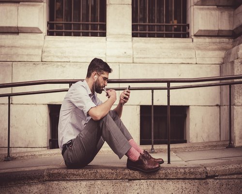 Young adult checking notifications on a smartphone during an urban transit stop